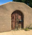 Wooden arched door in adobe wall
