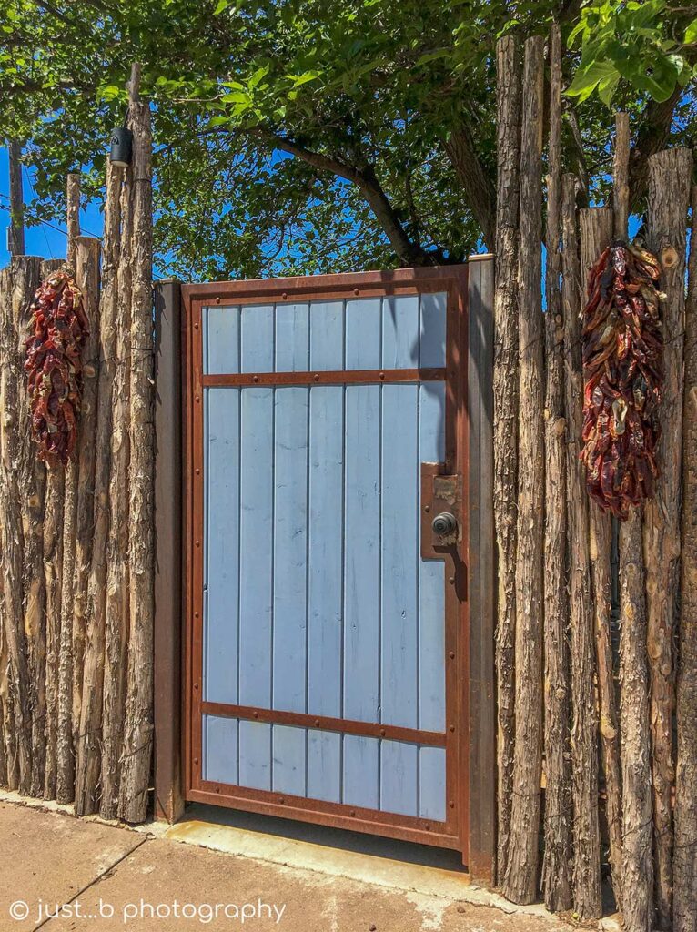 Blue door in coyote fence with Chile ristras