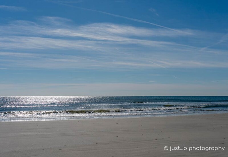 Winter beach scene with sun reflections on calm Atlantic ocean.