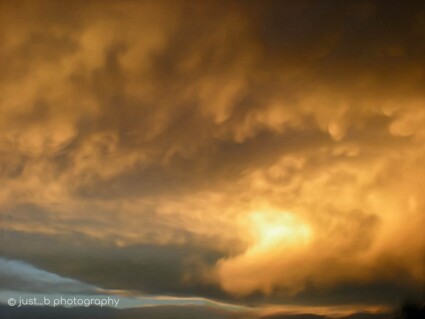 Dark, rolling storm clouds enveloping the sun at sunset over Golden, CO.